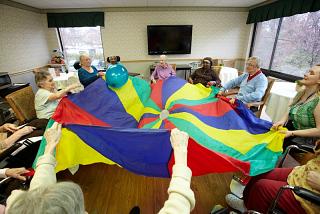 Team of older people playing with an open parachute