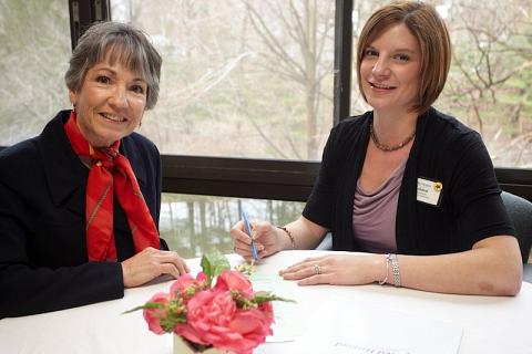 Two women sitting at a fancy, white table-clothed table