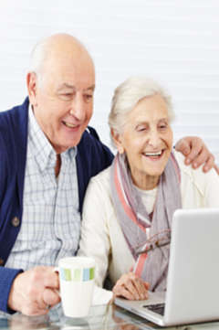 two seniors smiling at a computer screen