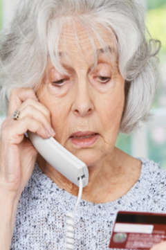 older woman on the phone looking at her credit card