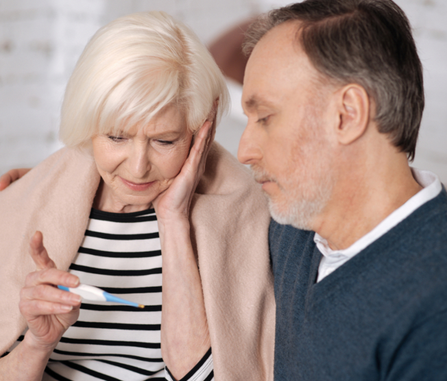 senior couple looking at thermostat