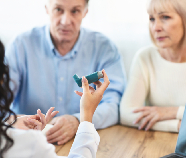 doctor showing inhaler to husband and wife