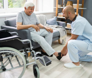 nurse putting on senior man's shoes