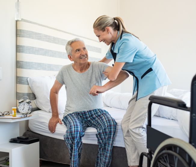 nurse assisting senior man to get up from bed