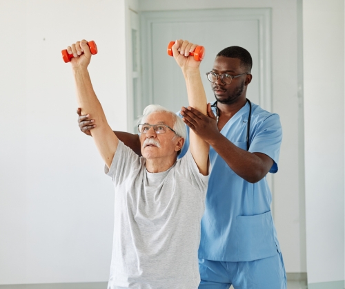 rehabilitation therapist assisting senior man with dumbbells
