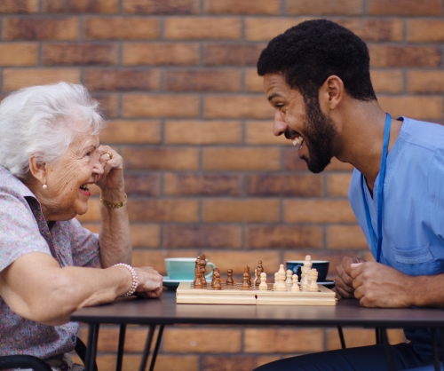 caregiver playing chess with elderly woman